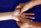 hand undergoing massage with two thumbs on pressure point